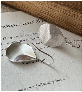 Detailed macro view of S925 sterling silver leaf earrings with a brushed metal texture