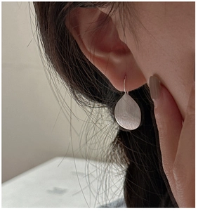Macro shot of minimalist S925 sterling silver leaf earrings with brushed metal finish