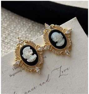 Macro shot of vintage cameo earrings with gold filigree and crystal embellishments