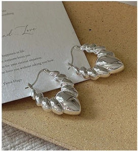 Macro shot of S925 sterling silver twisted croissant hoop earrings with mirror finish