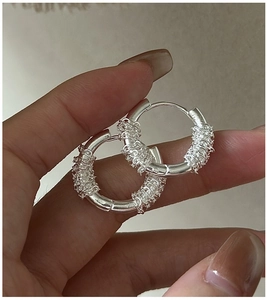 Detail of S925 sterling silver woven hoop earrings with textured twisted wire design