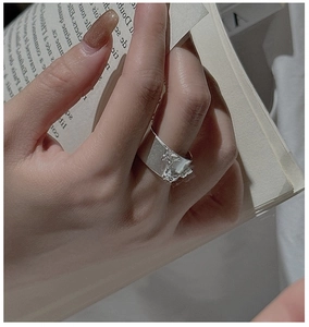 Gros plan détaillé sur une bague papillon en argent mat portée à la main d'un mannequin