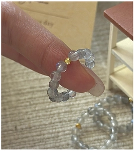 Macro detail of elastic moonstone beaded ring with a gold faceted metal accent bead