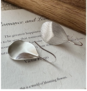 Close-up of S925 sterling silver teardrop earrings with a brushed metal texture finish