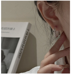 Close-up of S925 sterling silver woven texture hoop earrings worn on model's ear