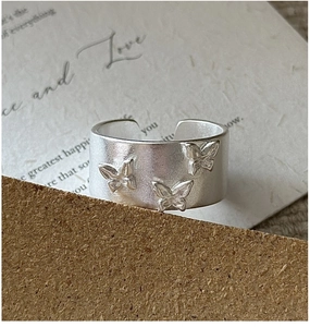 Vue macro d'une bague large en argent 925 avec trois motifs de papillons 3D en relief