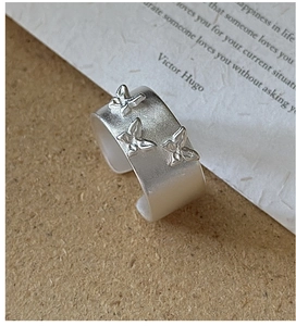 Détail macro d'une bague large en argent 925 mat avec motifs papillons en relief et anneau