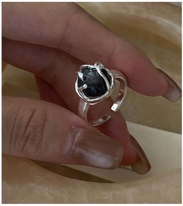 Primer plano de anillo de plata S925 con piedra obsidiana y textura de lava