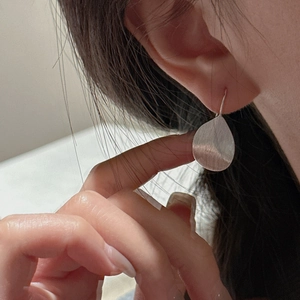 S925 sterling silver leaf drop earrings with brushed texture on model's ear