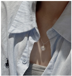 Close-up of a large white round shell pearl pendant on a slim S925 sterling silver chain