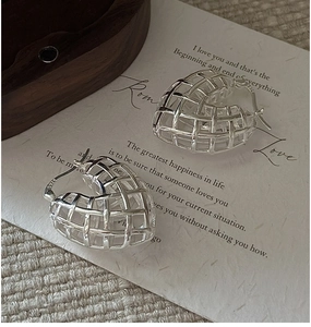 Makroaufnahme von S925 Sterling Silber hohlen Herzohrringen auf Vintage Papier Hintergrund