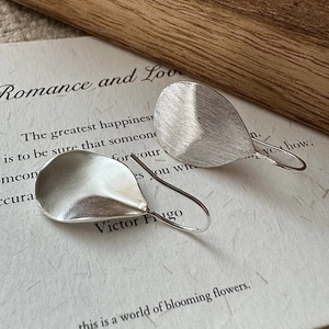 Minimalist S925 sterling silver leaf earrings with brushed texture on art paper background