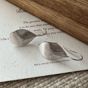 S925 sterling silver leaf earrings with brushed texture on artistic paper and wood