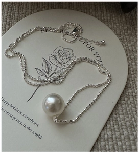 Detail of S925 silver chain necklace with a large white pearl on a decorative card