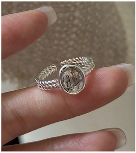 Macro shot of oval black rutilated quartz on a twisted silver rope texture ring