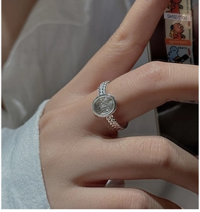 Detail of vintage S925 silver ring with braided band and engraved shield on finger