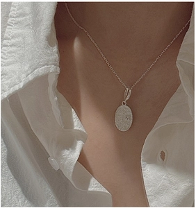 Detail of a minimalist S925 sterling silver daisy pendant necklace on a model
