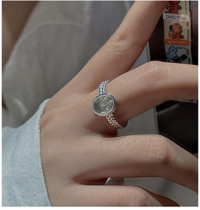 Macro shot of silver woven chain ring with vintage oval grey stone on a hand