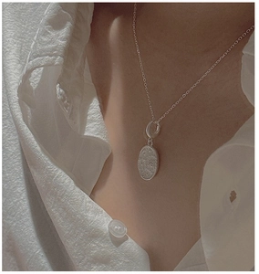 Close-up of S925 sterling silver daisy flower oval pendant on a model wearing white shirt