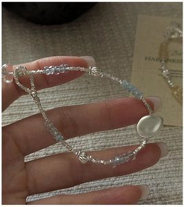 Detail of beaded S925 silver bracelet featuring aquamarine stones on a woven texture