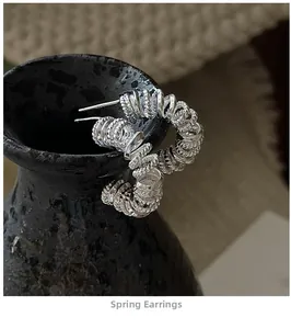 Vue macro de créoles ressort en argent avec texture brossée sur céramique sombre