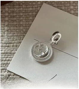 Detail of S925 silver vintage moon and star pendant with beaded edge on fabric background