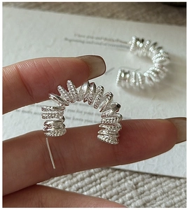 Détail des boucles d'oreilles créoles torsadées argentées à texture corde
