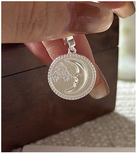 Macro view of S925 silver star and moon disc pendant with zircon stones and milgrain edges