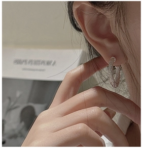 Gros plan d'une boucle d'oreille créole torsadée en argent S925 montrant la texture