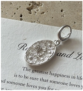 Macro detail of S925 sterling silver daisy pendant with embossed floral and zircon stone