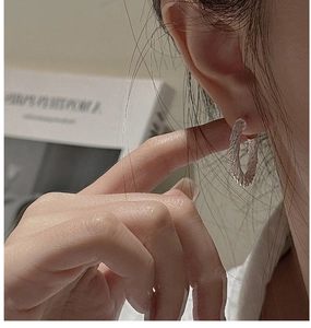 Gros plan de la boucle d'oreille créole torsadée en argent montrant sa texture