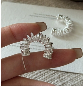 Vue macro de boucles d'oreilles spirales torsadées en argent S925 avec texture métallique