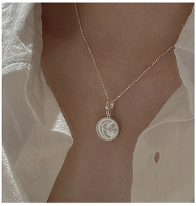 Detail of S925 sterling silver star and moon pendant necklace worn on neck