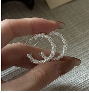 Gros plan de boucles d'oreilles créoles torsadées en argent avec texture tressée