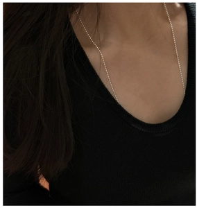 Close-up of minimalist S925 sterling silver beaded sweater chain worn on neck