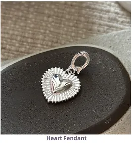 Macro shot of silver heart pendant with textured edges and spring clasp on stone
