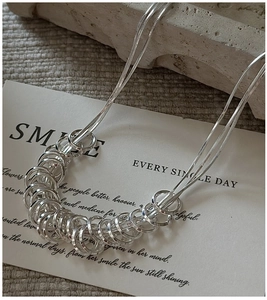 Detail of S925 silver double-layered snake chain with intertwined ring pendants