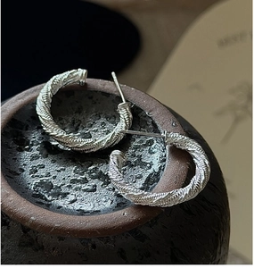 Gros plan de créoles en argent sterling S925 avec un design vintage à texture torsadée