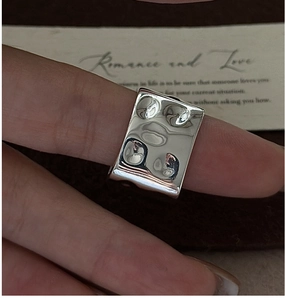 Close-up of silver square ring featuring unique hammered texture and industrial design