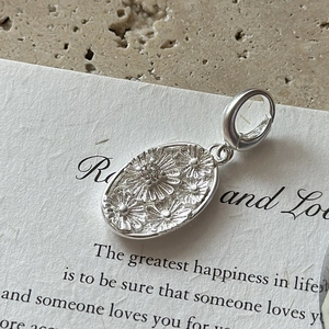 S925 sterling silver oval daisy pendant with sparkling zircon on a textured stone background