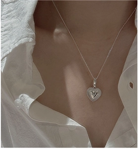 Close-up of S925 sterling silver heart pendant necklace with sunburst texture on a model