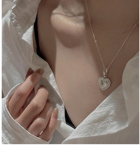 Detail of S925 sterling silver heart necklace with sunburst texture on a model