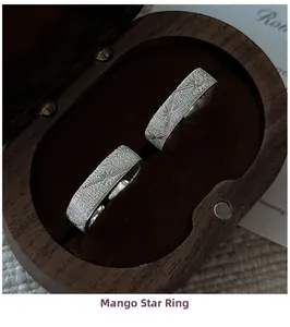 Detail of brushed silver hexagram rings with minimalist engraved cross star patterns