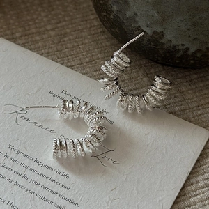 Boucles d'oreilles spirales minimalistes en argent S925 sur papier vintage texturé