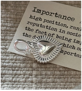 Detailed close-up of a silver heart pendant with lobster clasp and sunburst texture