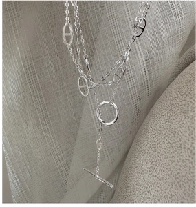 Macro shot of silver pig-nose links with a T-bar clasp and circular ring on soft linen