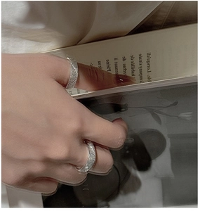 Detailed close-up of matte silver rings with star engravings worn on a finger