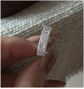 Macro shot of silver textured star-engraved ring on knit background with detail
