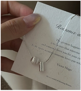Detail of S925 sterling silver necklace featuring a matte bead and polished cylinder pendant