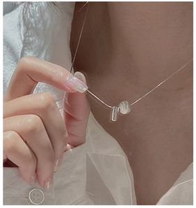 Macro shot of S925 silver necklace with minimalist cylinder and cat-eye bead charms